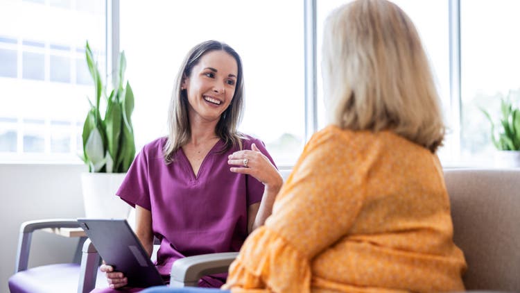 A woman smiles and talks to another woman