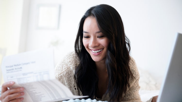 A woman smiles while looking down at papers