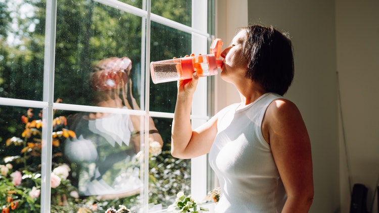 A woman drinks from a water bottle