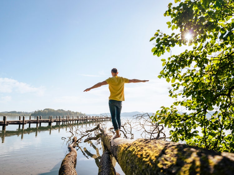 man walking and balancing on a tree