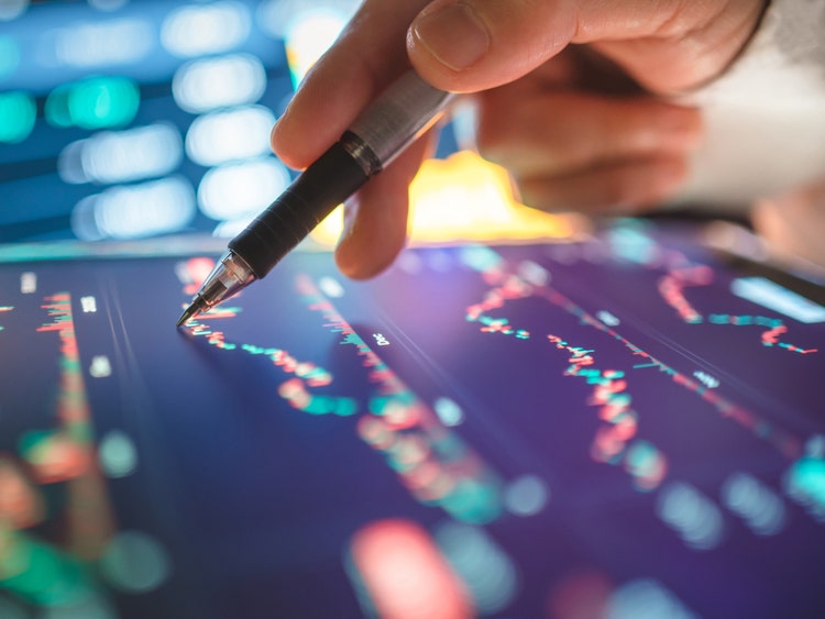 Person tracing market performance on iPad with pen