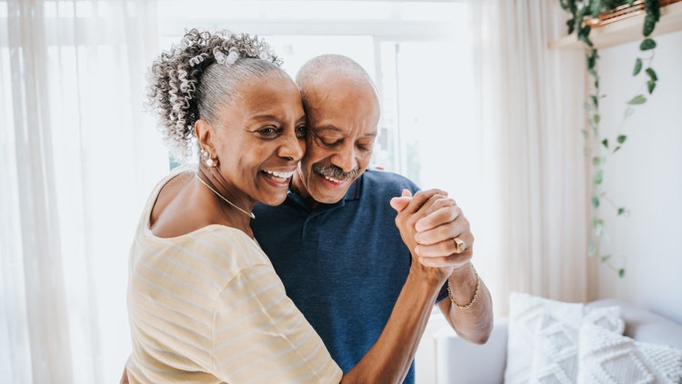 An elderly couple smiles and dances together